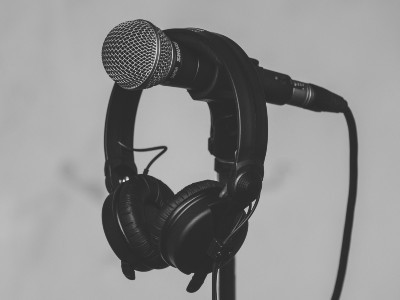 Mikrofon und Kopfhörer in schwarz vor grauem Hintergrund.