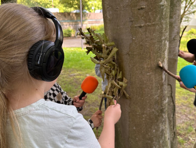 Kinder halten Mikrofone an einen Baum
