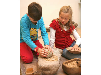 KulturAbo Kinder mahlen Getreide auf Steinzeitart im ArchaeologischenMuseum