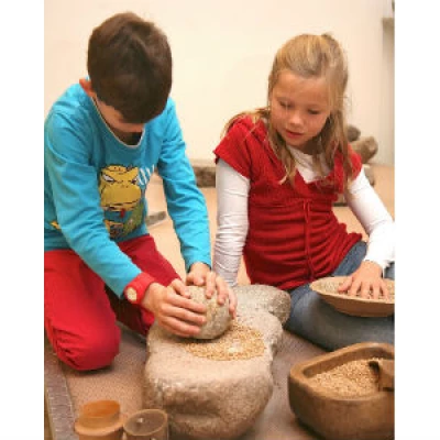 KulturAbo Kinder mahlen Getreide auf Steinzeitart im ArchaeologischenMuseum