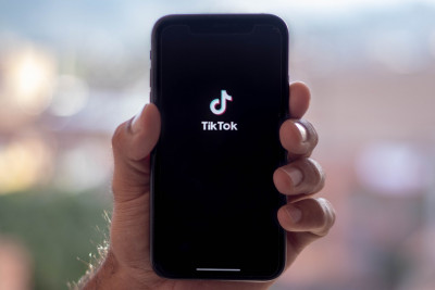 Hand hält Handy mit TikTok-Logo