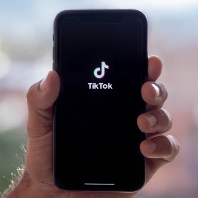 Hand hält Handy mit TikTok-Logo