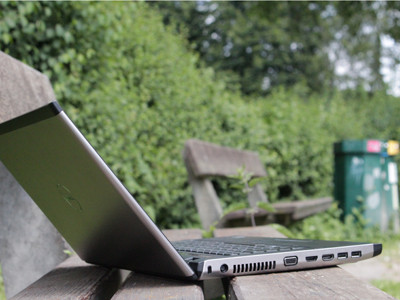 Ein Laptop steht aufgeklappt auf einer Parkbank