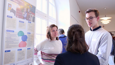 Studierende stehen vor einem Poster und diskutieren