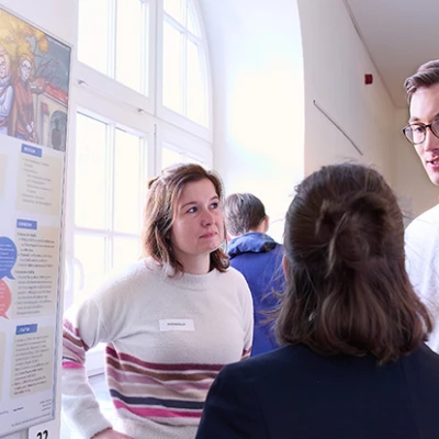 Studierende stehen vor einem Poster und diskutieren