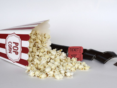 verschüttetes Popcorn auf weißer Fläche; daneben Tickets und Film-Negativ