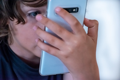 Kind hält Smartphone ganz nah vors Gesicht